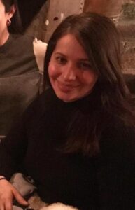 Image Of A Woman With Dark Hair Wearing Black And Smiling At The Camera