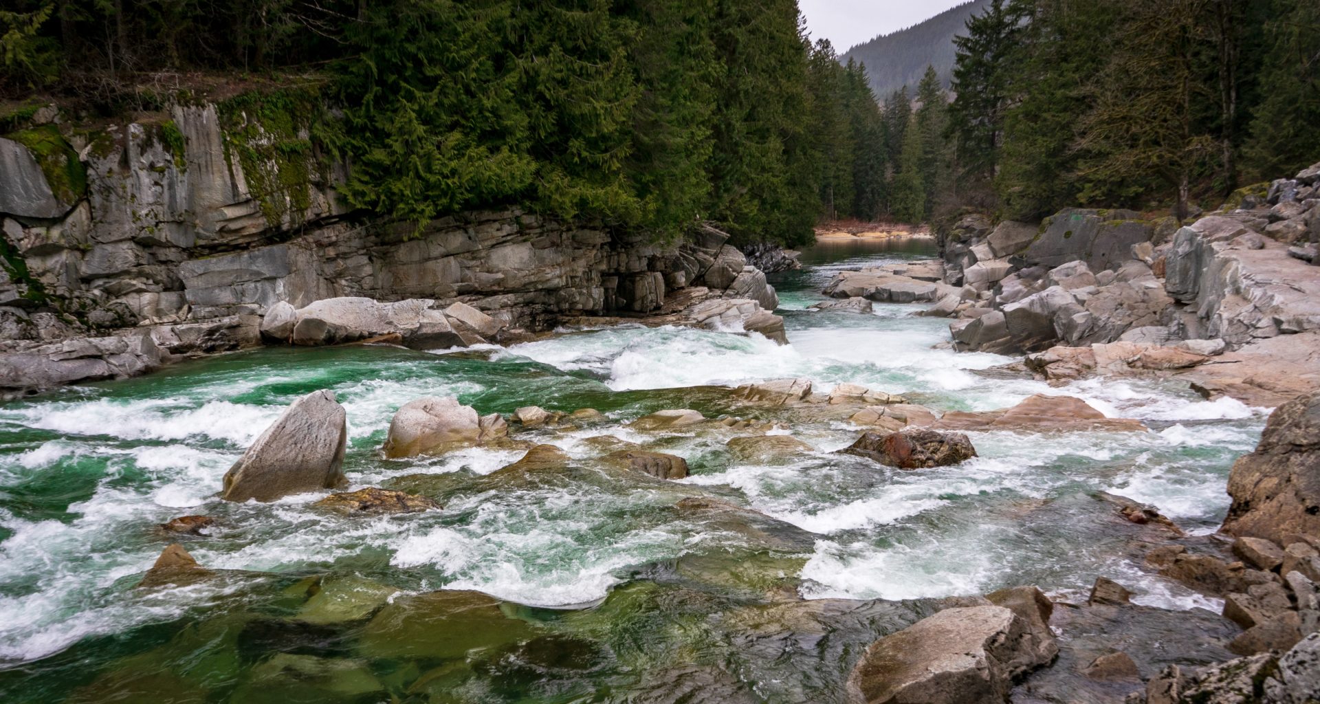 Blue-green river flowing over rocks. Trees in the background.