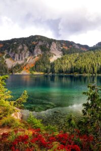 Fall colors in foreground, blue-green lake in the middle, mountain in the background